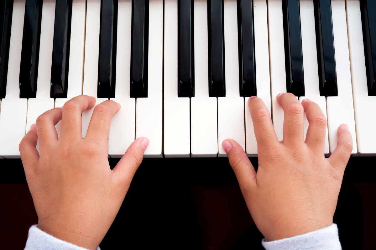 Girl playing piano. Closeup hands, top view. Art and music backg