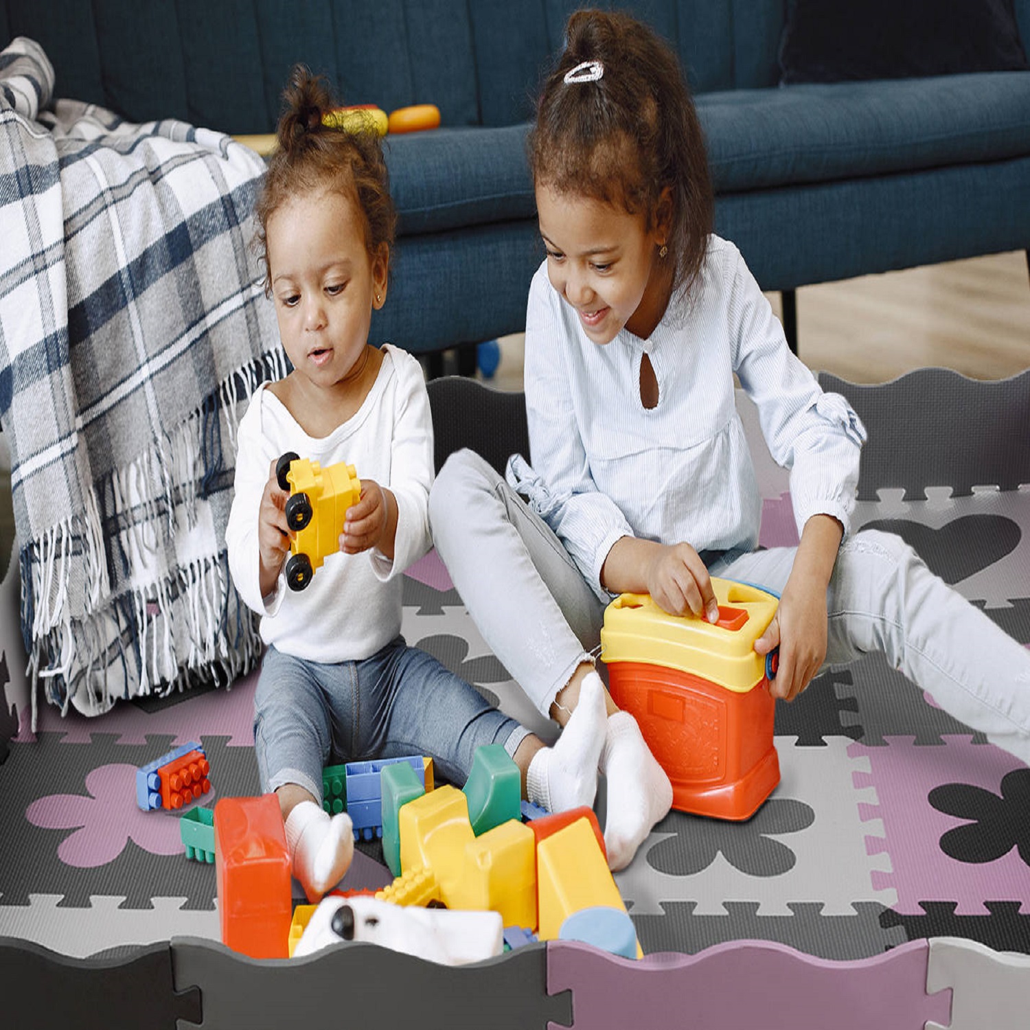 Cute little girls playing with toys on the floor near the couch