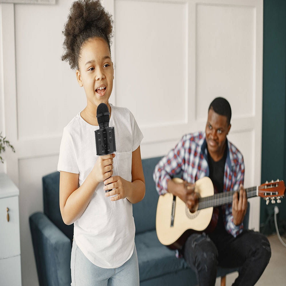 Dad is sitting with a guitar and daughter with a microphone
