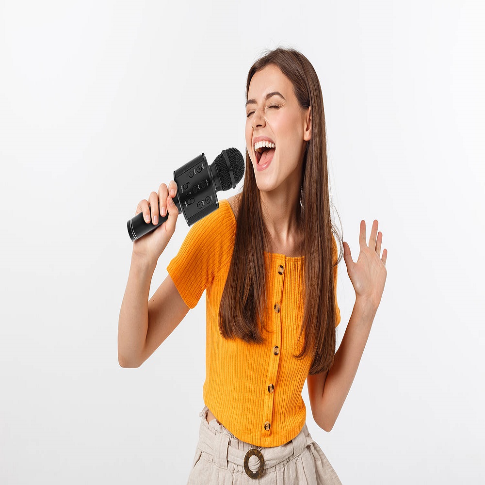 Young pretty woman happy and motivated, singing a song with a microphone, presenting an event or having a party, enjoy the moment